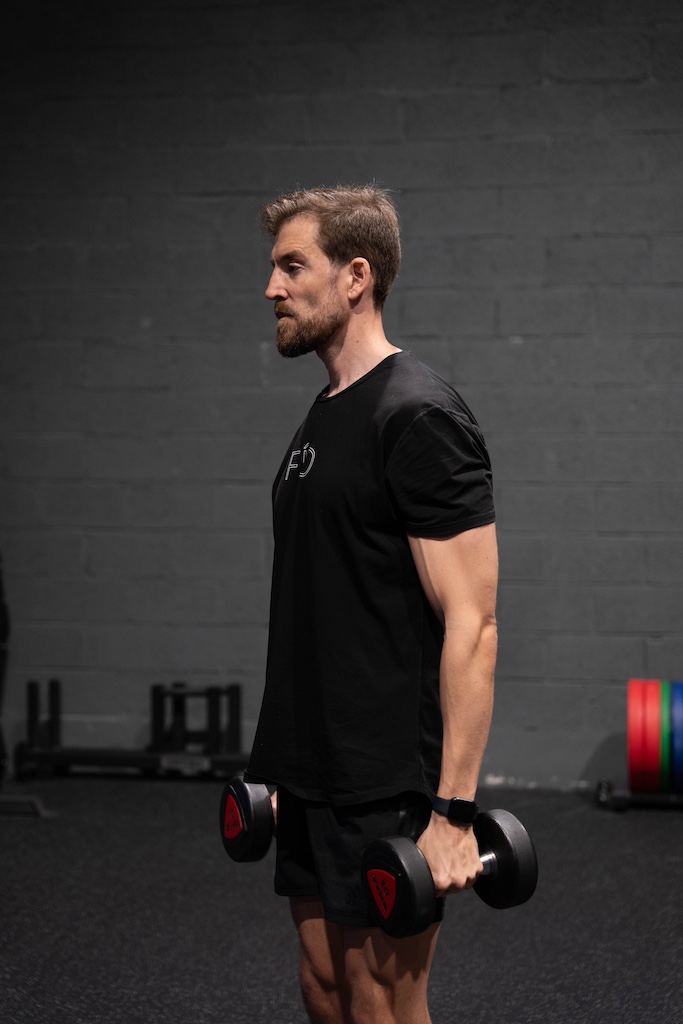 PT demonstrating how to perform a dumbbell single-arm curl in a workout routine for beginners