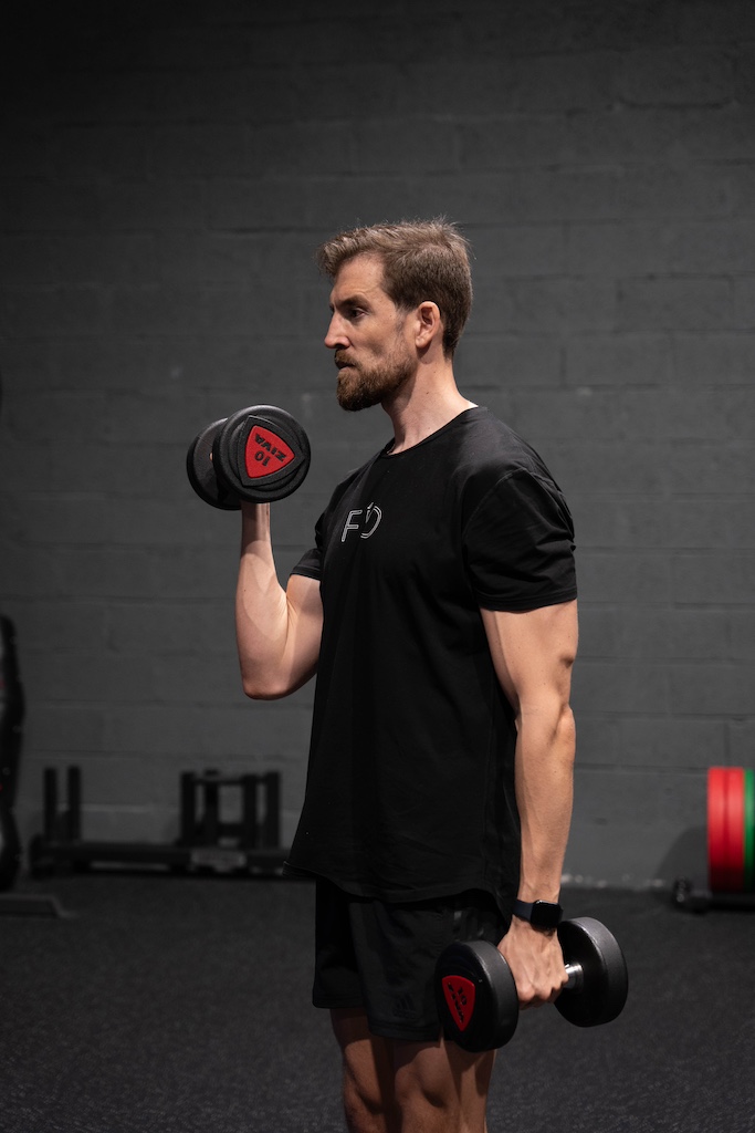 PT demonstrating how to perform a dumbbell single-arm curl