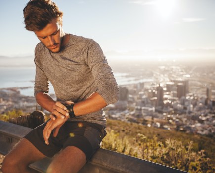 Young man checking his fitness watch on a run