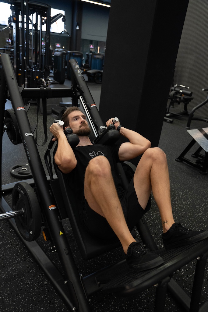 PT demonstrating how to perform a hack squat in a workout routine for beginners