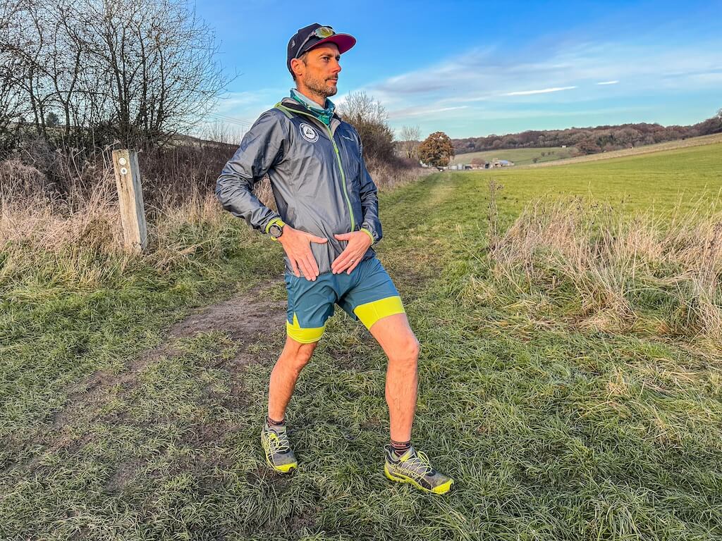 Running coach Simon James performing hip flexor stretch in a field after a trail run