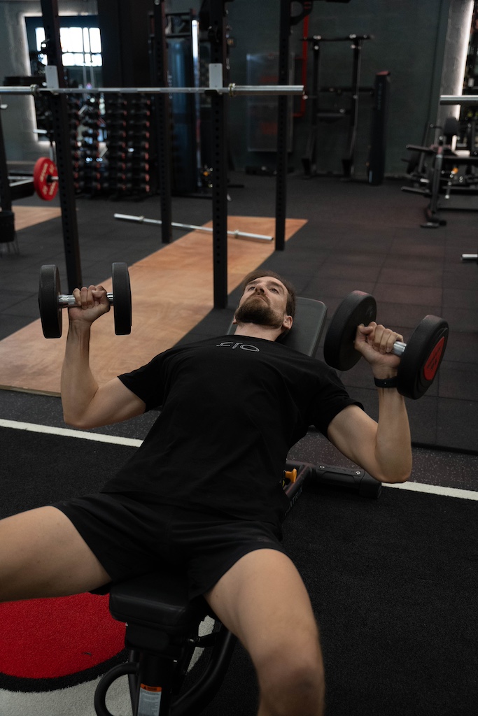 PT demonstrating how to perform a incline dumbbell bench press in a workout routine for beginners