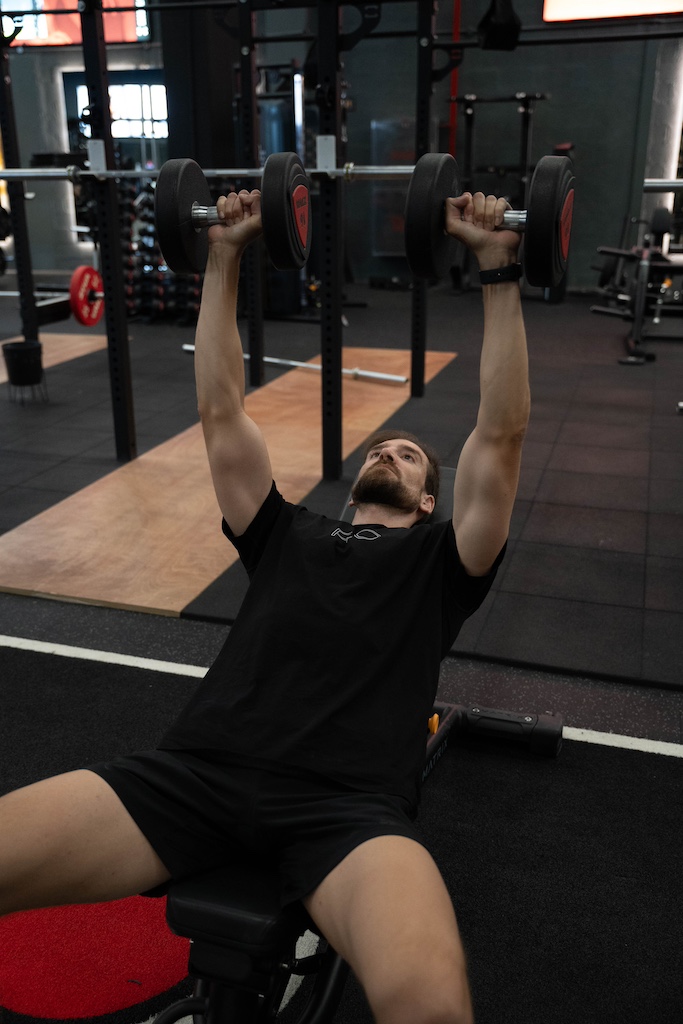 PT demonstrating how to perform an incline dumbbell bench press in a workout routine for beginners