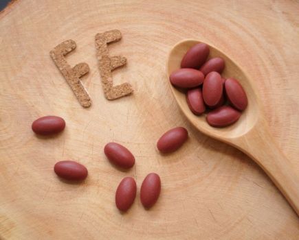 Wooden spoon and iron supplement tablets with the letters 'FE'