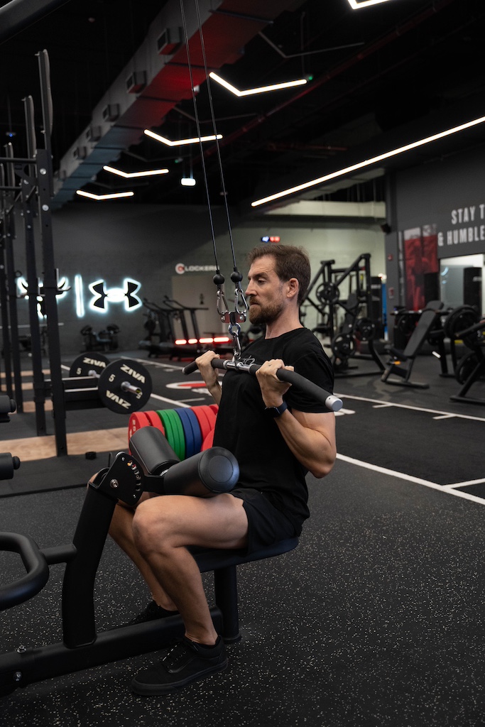 PT demonstrating how to perform a lat pulldown with narrow grip in a workout routine for beginners