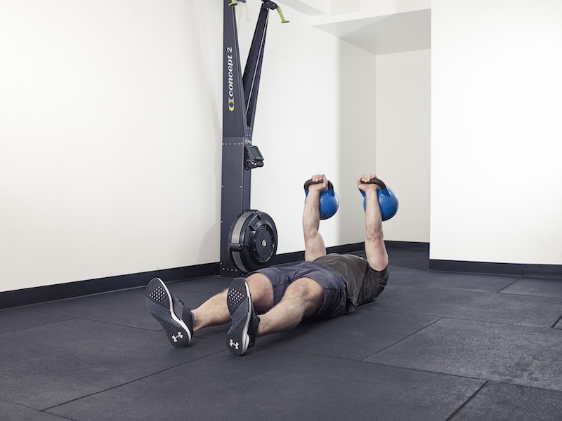 fitness model demonstrating how to perform a kettlebell angel press – one of the best kettlebell abs exercises