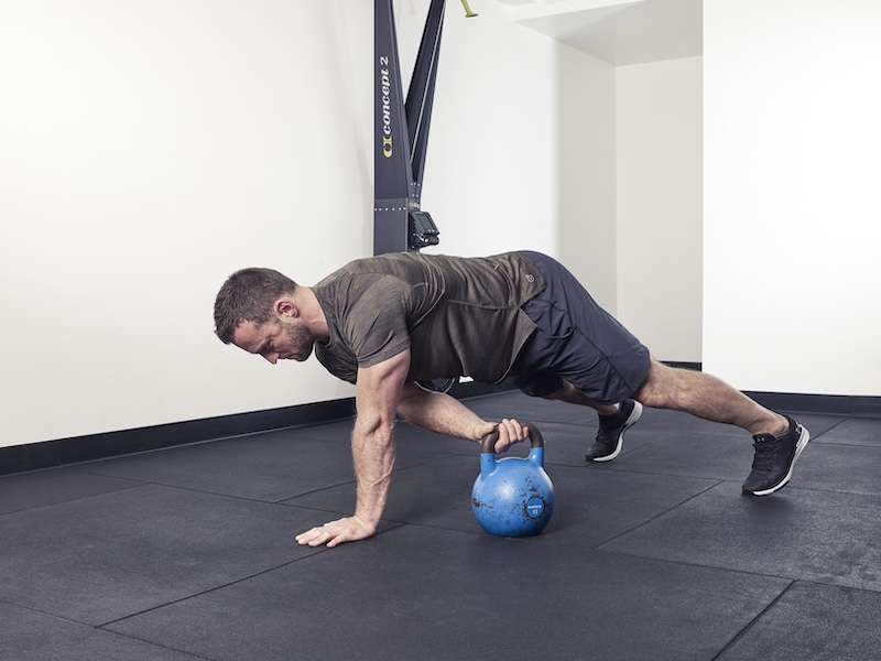 fitness model demonstrating how to perform a kettlebell plank pass – one of the best kettlebell abs exercises