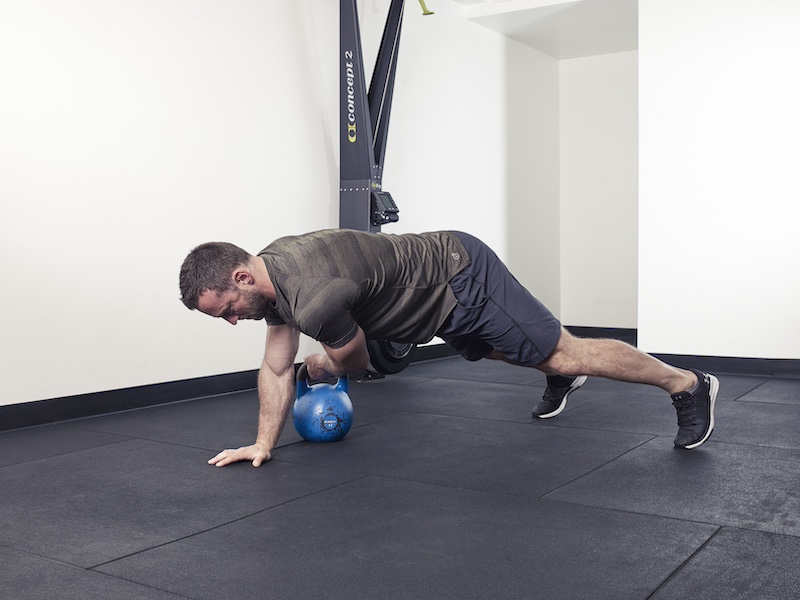 fitness model demonstrating how to perform a kettlebell plank pass – one of the best kettlebell abs exercises