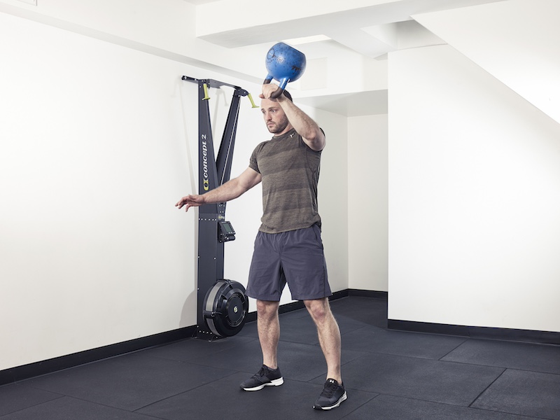 fitness model demonstrating how to perform a kettlebell snatch