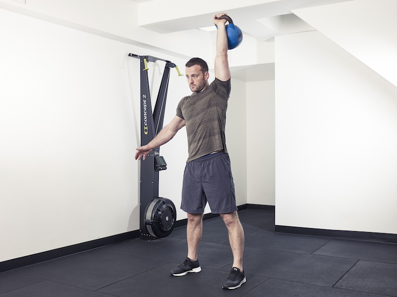 fitness model demonstrating how to perform a kettlebell snatch