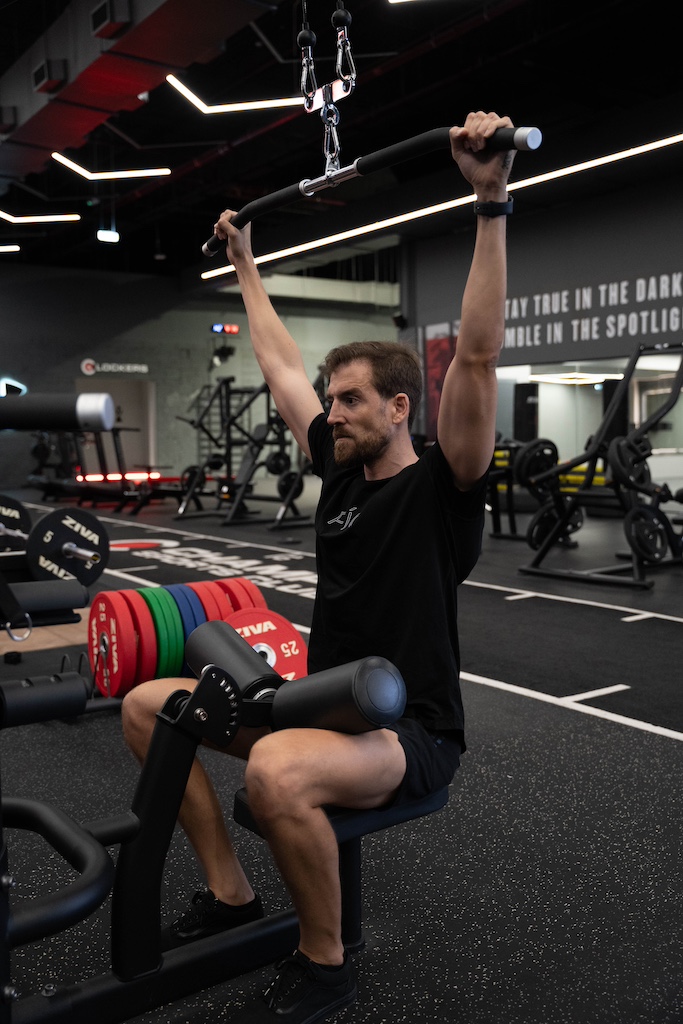 PT demonstrating how to perform a lat pulldown in a workout routine for beginners