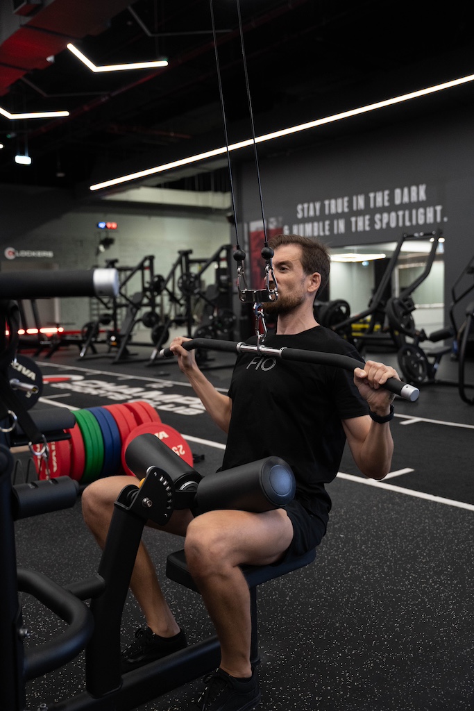 PT demonstrating how to perform a lat pulldown in a workout routine for beginners