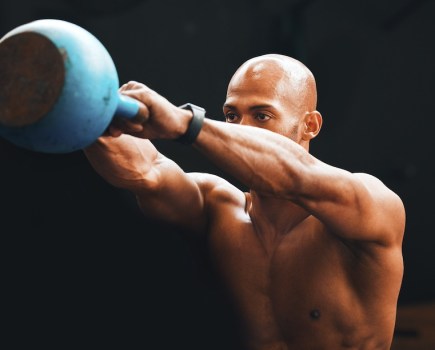 topless man performing kettlebell swing as part of a beginners kettlebell workout