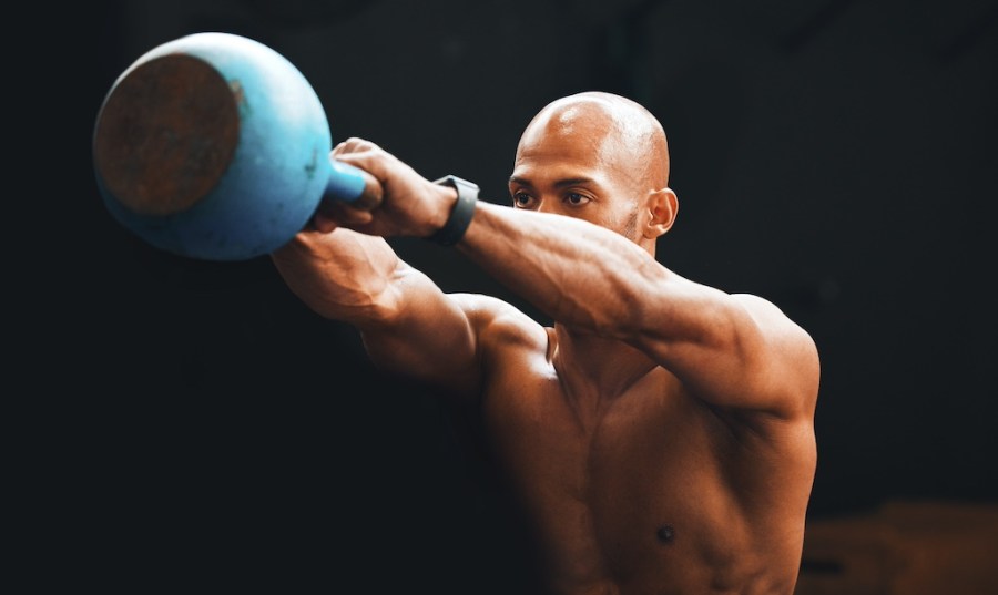 topless man performing kettlebell swing as part of a beginners kettlebell workout