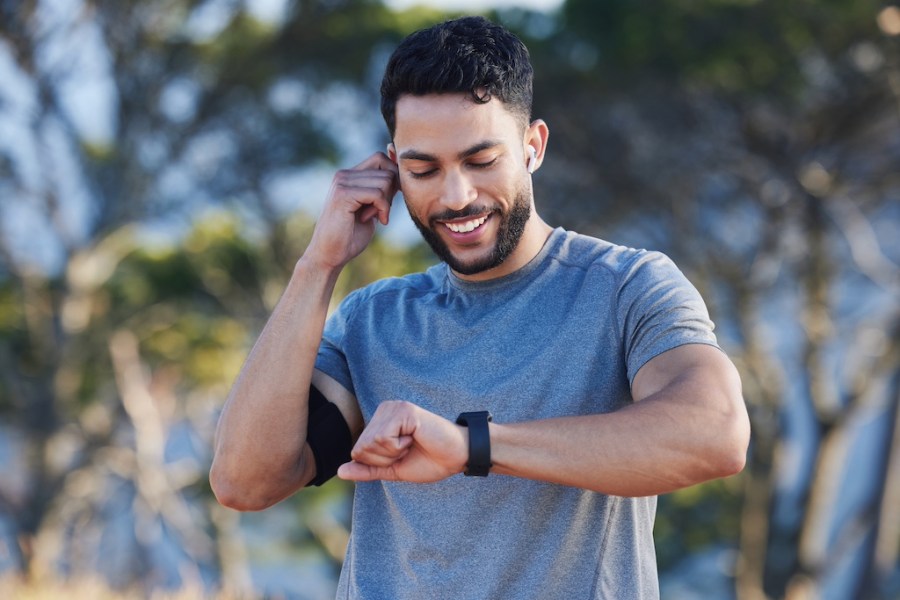 man looking at sports watch with headphones in