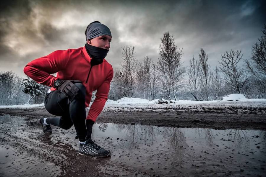 man in running kit crouched down on a cold wintery day