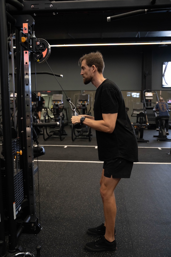 PT demonstrating how to perform a triceps pushdown