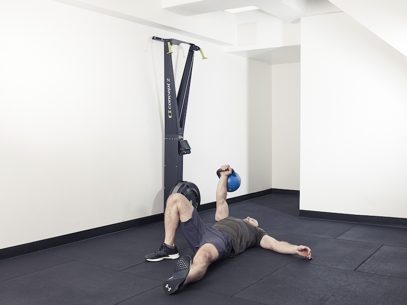 fitness model demonstrating how to perform a kettlebell Turkish get-up