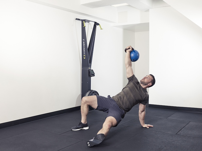 fitness model demonstrating how to perform a kettlebell Turkish get-up