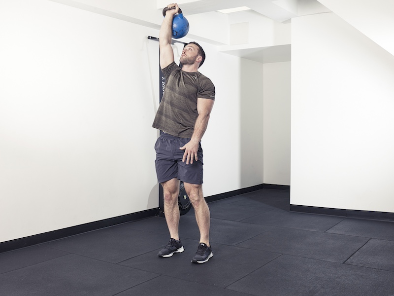 fitness model demonstrating how to perform a kettlebell Turkish get-up