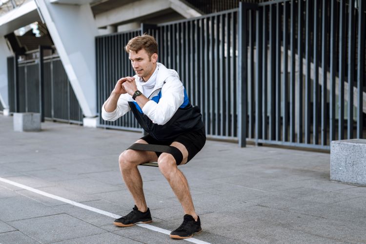 Man performing resistance band leg exercises outside