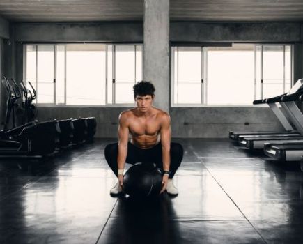 Slim man exercising in gym with medicine ball