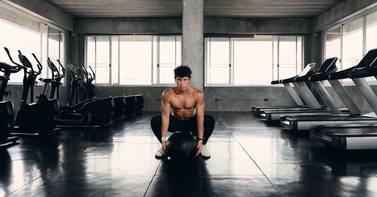 Slim man exercising in gym with medicine ball