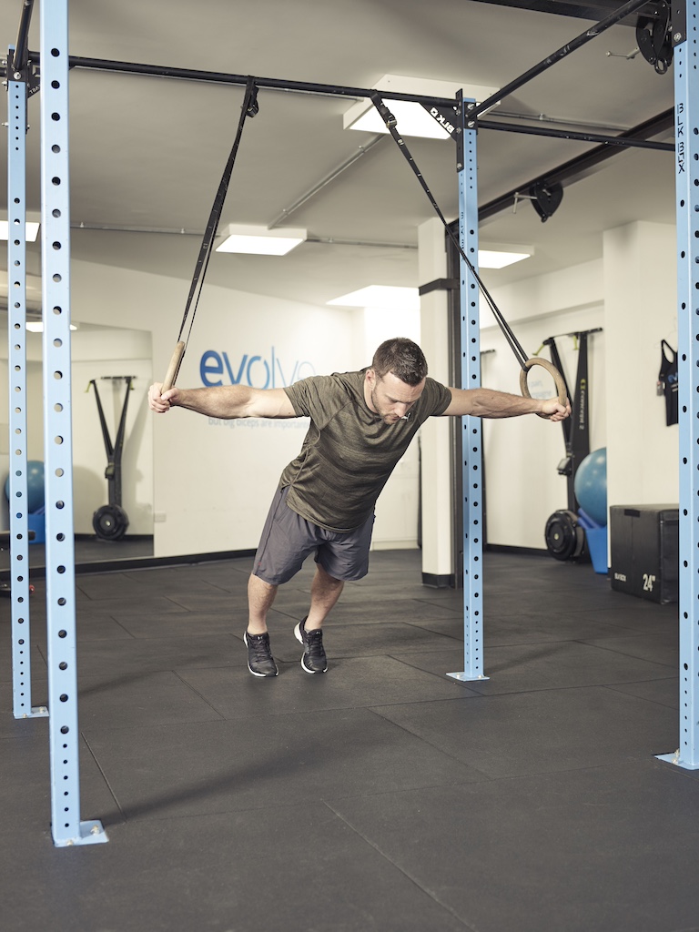 man performing a flye with a suspension trainer