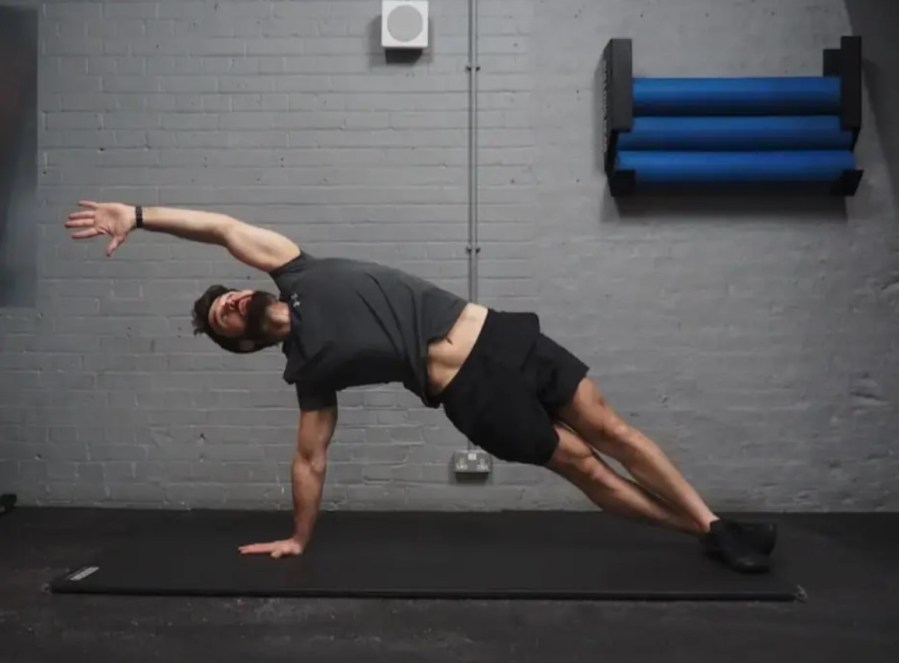 Man performing a high side plank with reach