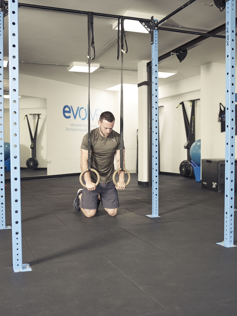 man performing a kneeling rollout 