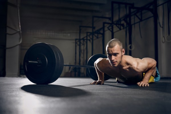 Man performing push-ups next to a barbell