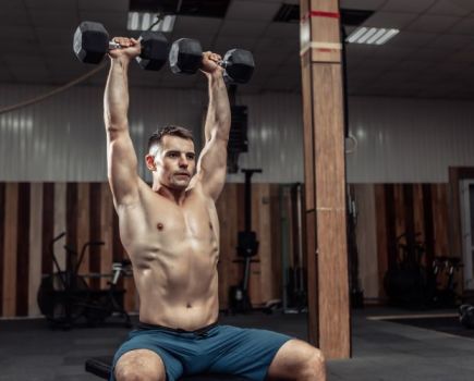 Man in a gym performing a seated dumbbell press