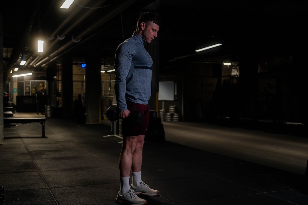 man performing dumbbell deadlift in the gym