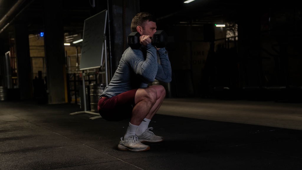 man performing dumbbell thruster as part of a small-space dumbbell workout