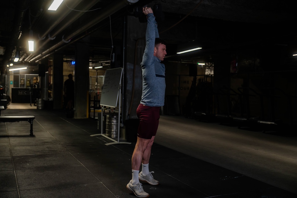 man performing dumbbell thruster as part of a small-space dumbbell workout