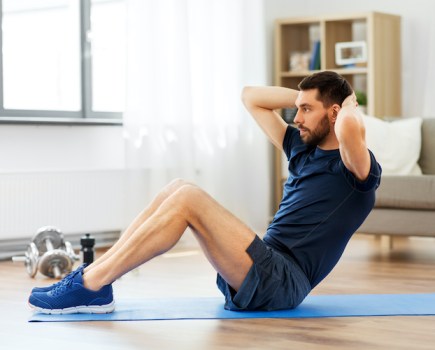 A man exercising by doing crunches at home