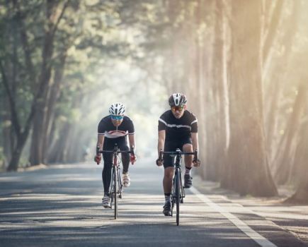 Two men cycling on forest road