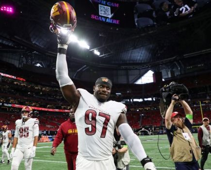 NFL player holding helmet aloft after a agame