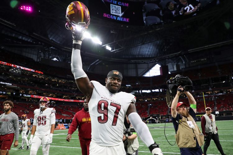 NFL player holding helmet aloft after a agame