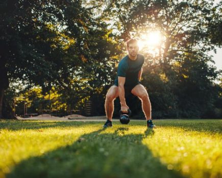 Man performing kettlebell swings in the park