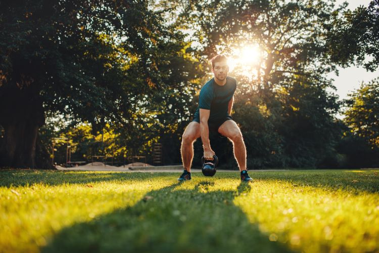 Man performing kettlebell swings in the park