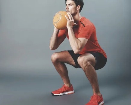 Man squatting while exercising with a kettlebell