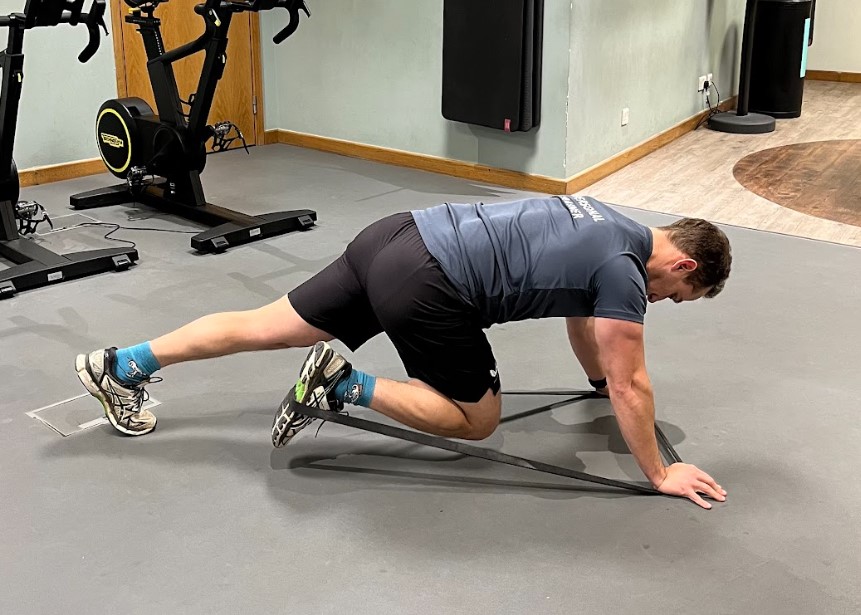 Man performing a resistance band plank kickback