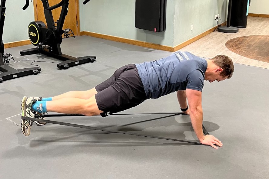 Man performing a resistance band plank kickback