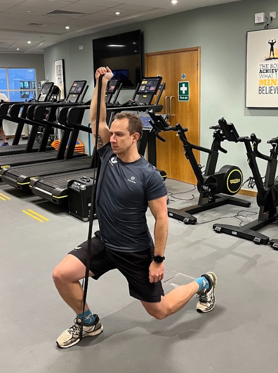 Man performing a resistance band raised reverse lunge