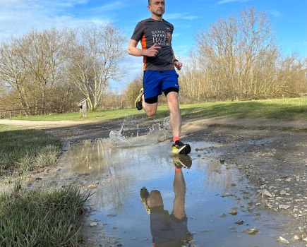 trail runner splashes through puddle while testing a pair of the Salomon S/Lab Genesis running shoes