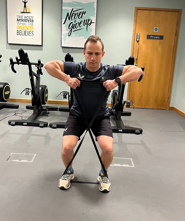 Man performing a resistance band side step with upright row hold