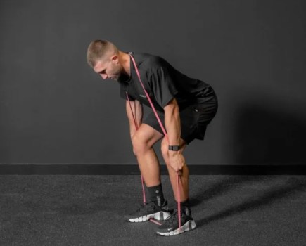 Man bending over working out with a resistance band