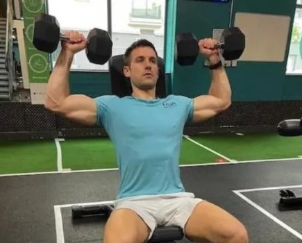 Close-up of man in a gym performing a shoulder press