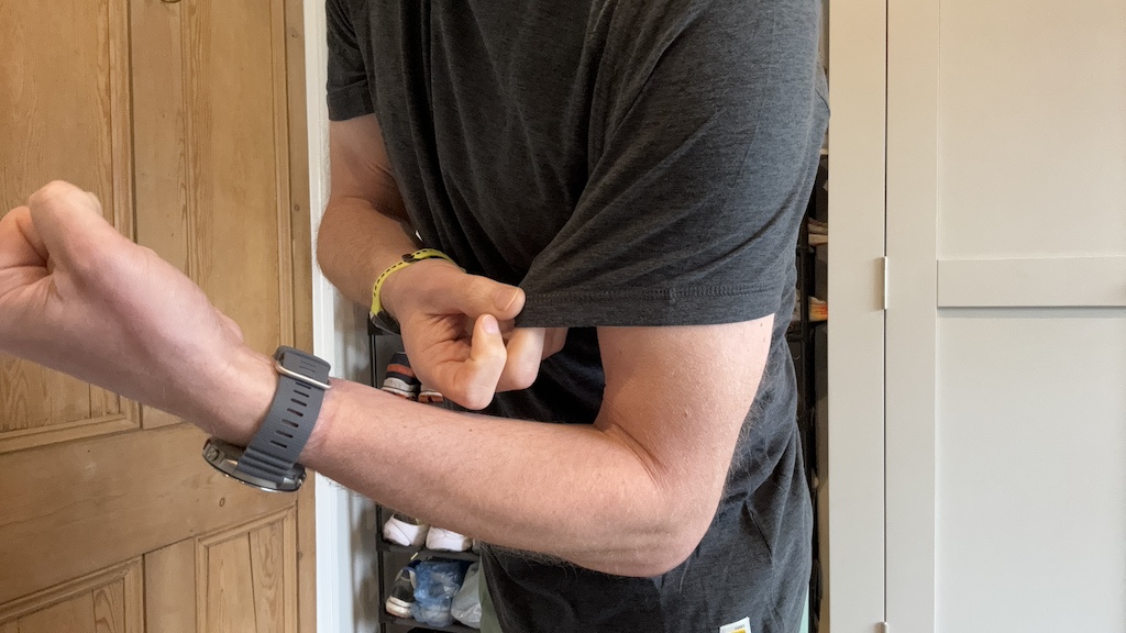 Man holding the sleeve of his workout top to show the stretchiness of the fabric